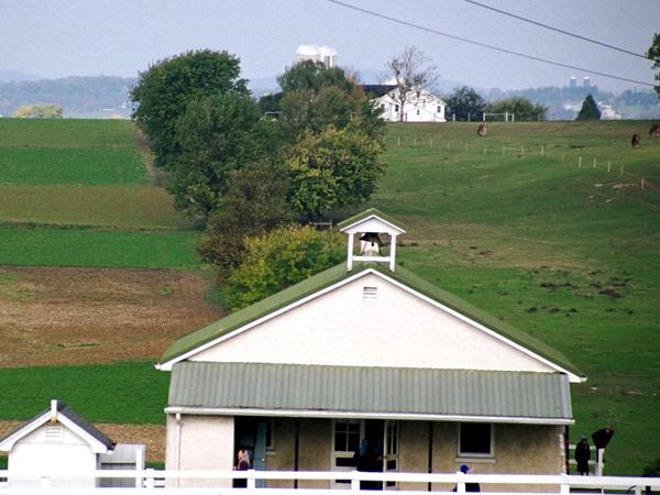 white exterior of an Amish home and rolling hills in Lancaster